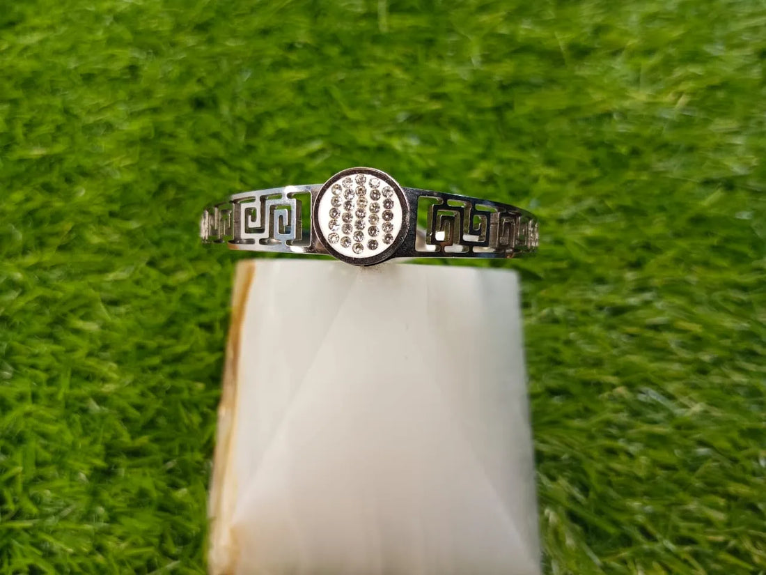 Silver ring with decorative band on a white stone against a green grass background