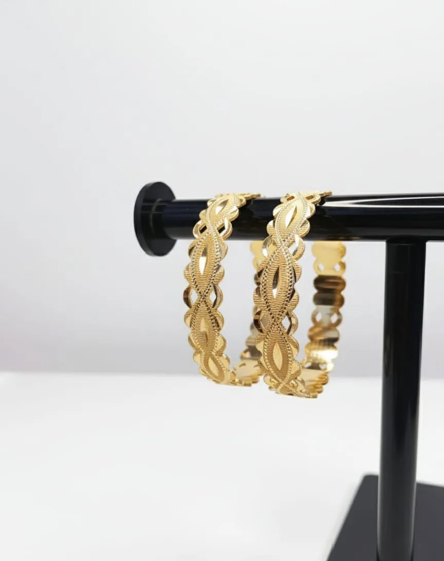 Gold bracelets on a hand with a green background