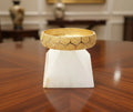 Gold bracelet on a white stand on a wooden surface