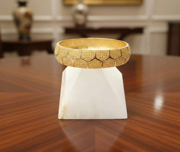 Gold bracelet on a white stand on a wooden surface