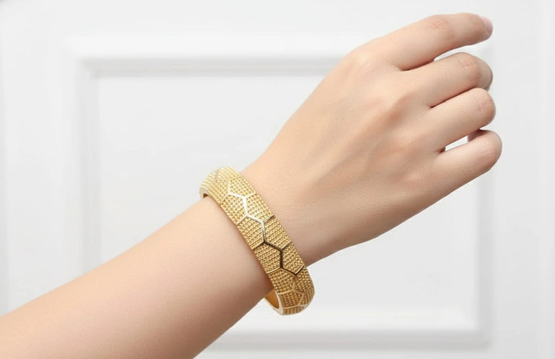 Gold bracelet on a white stand on a wooden surface
