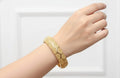 Gold bracelet on a wrist against a white background