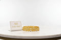 Gold bracelet on a white surface with a branded card in the background