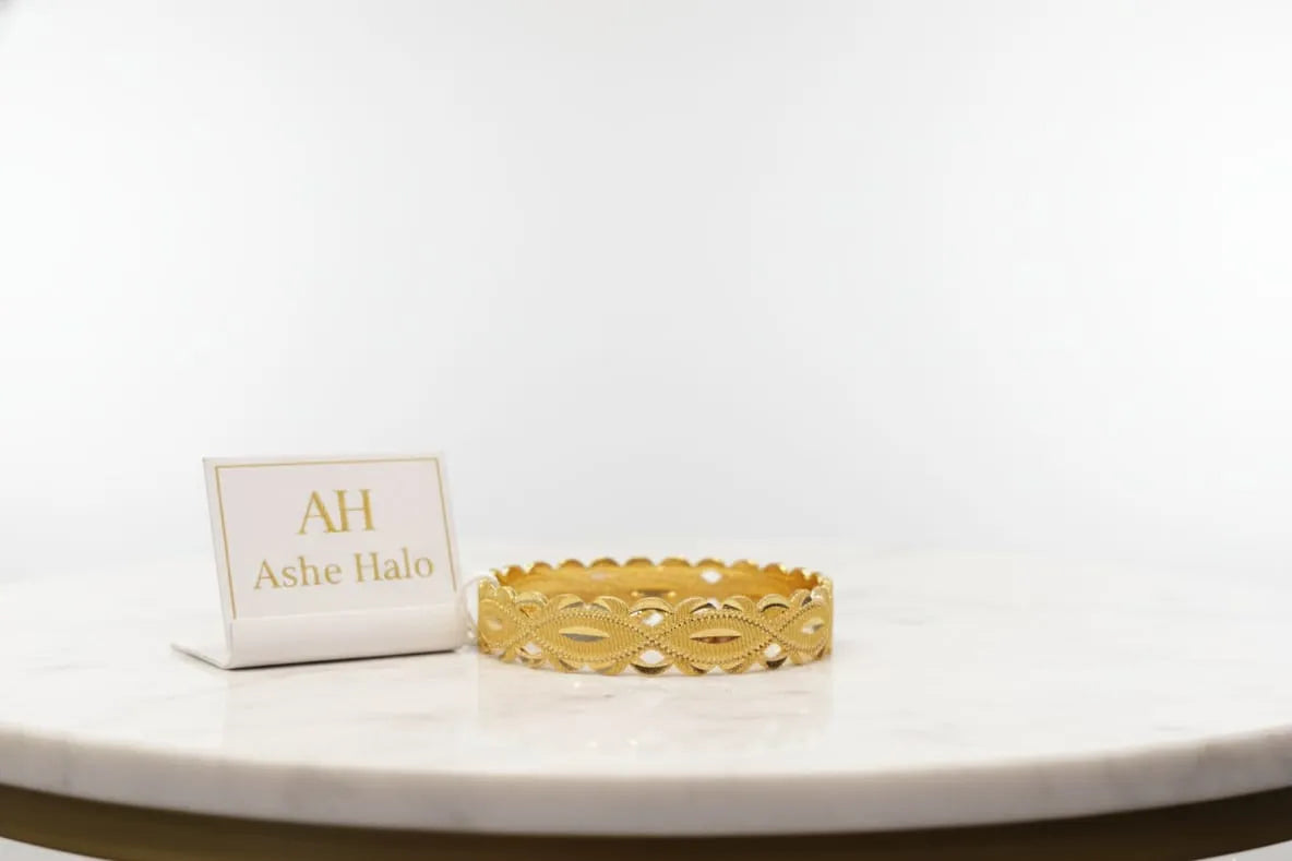 Gold bracelet on a white surface with a branded card in the background