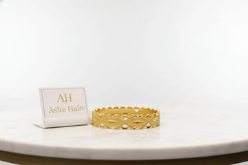 Gold bracelet on a white surface with a branded card in the background