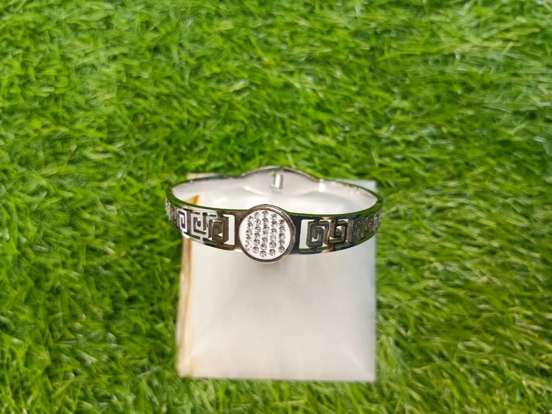 Silver ring with decorative band on a white stone against a green grass background