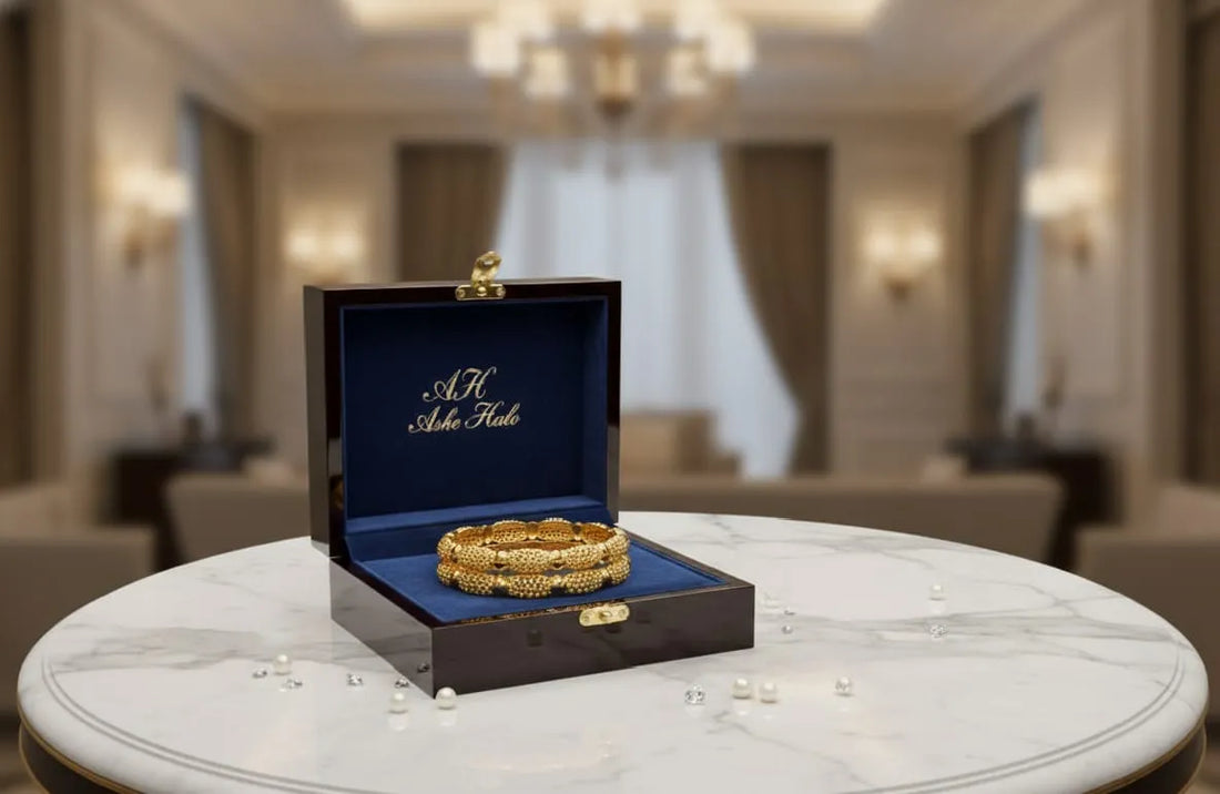 Gold bracelets in a branded box on a marble table with a blurred background