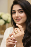 Woman wearing a gold ring with a floral design, holding her hand up to show the ring.
