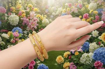 Hand wearing gold bracelets with a colorful floral background