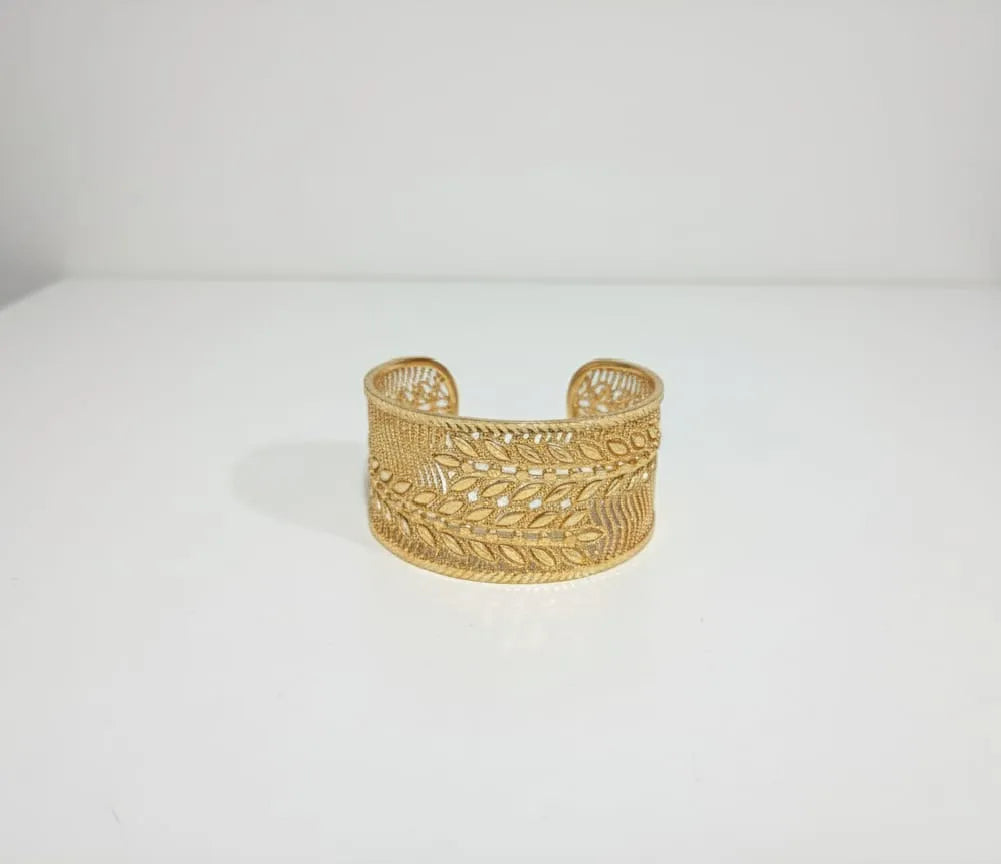 Gold bracelet on a hand against a green fabric background