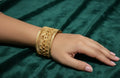 Gold bracelet on a hand against a green fabric background
