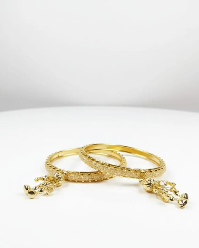 Two gold bracelets with intricate designs on a white background