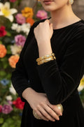 Person wearing gold bracelets with a blurred floral background
