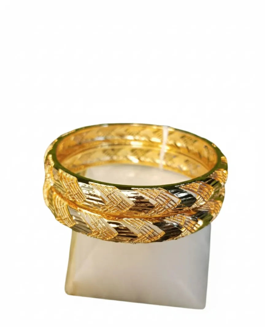 Person wearing gold bracelets with a blurred floral background