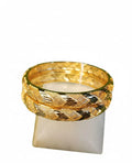 Gold bangle on a white candle with a white background