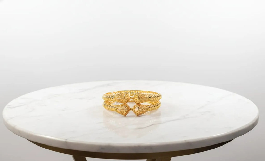Gold bracelet on a marble surface with a white background