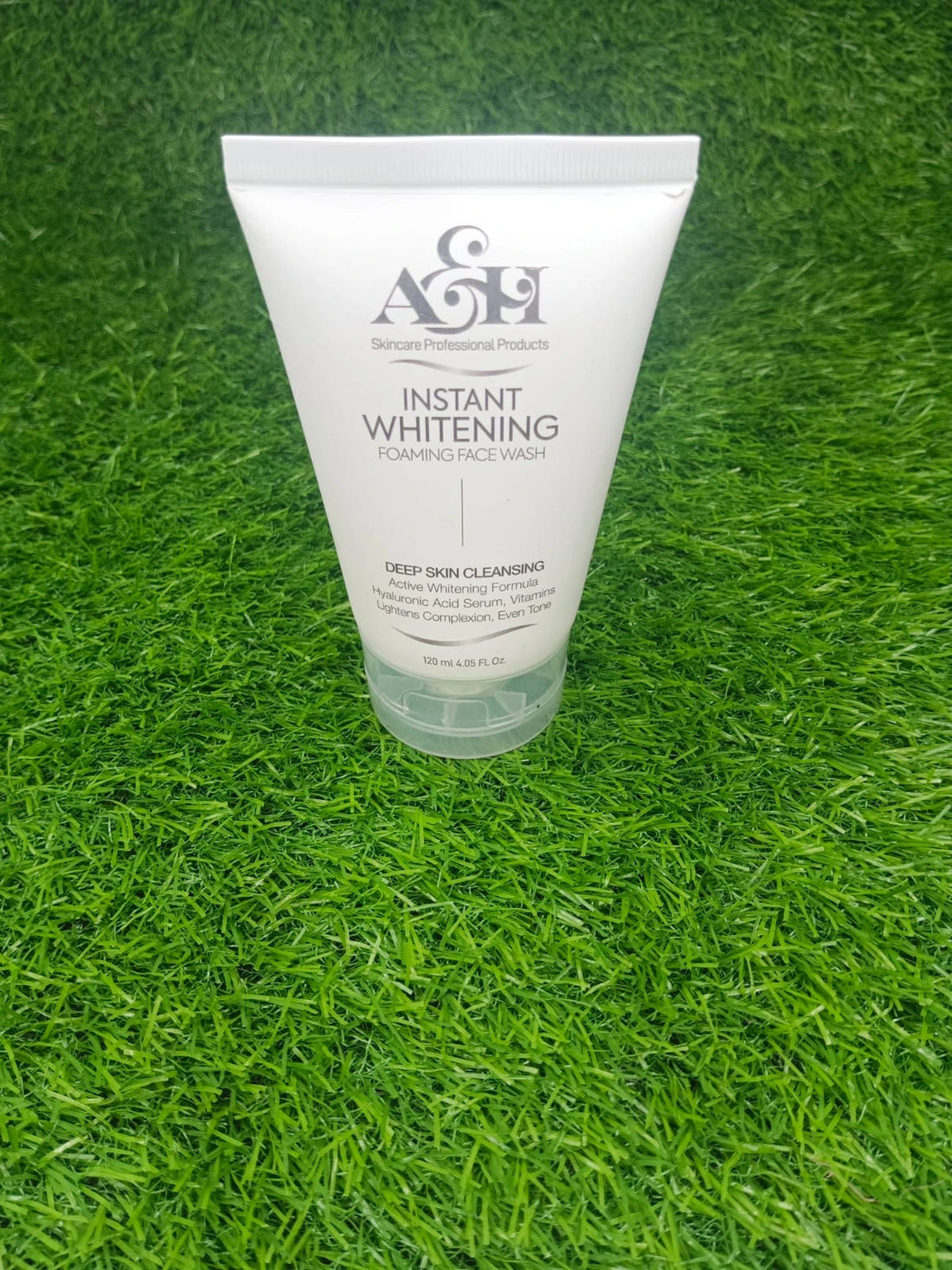 Tube of AGF Instant Whitening Deep Skin Cleanser on green grass