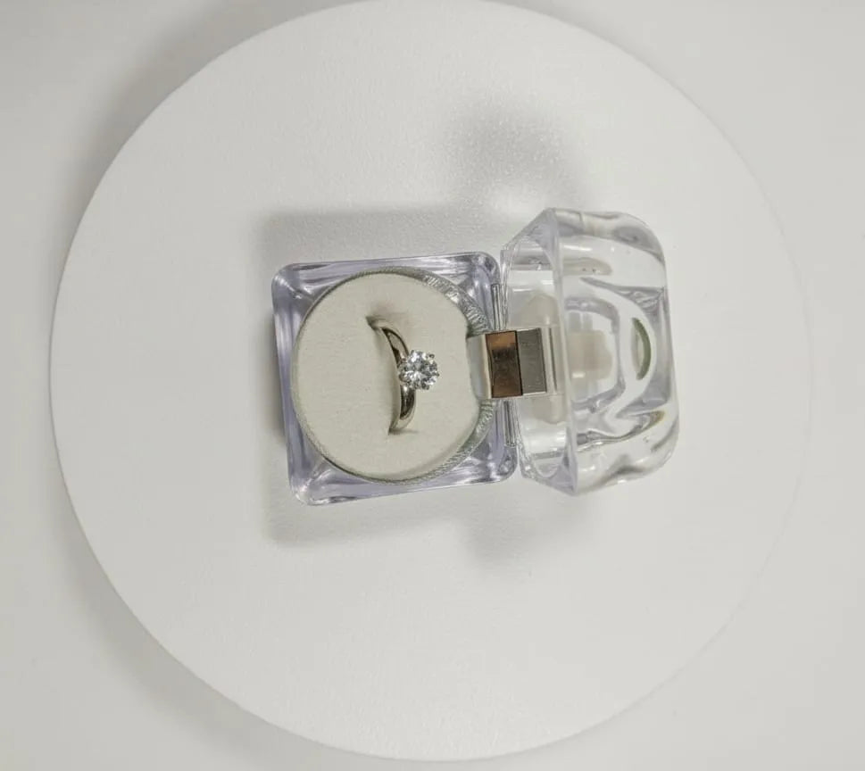 Hand wearing a ring with 'AH Ashe Halo' branding in a jewelry store setting