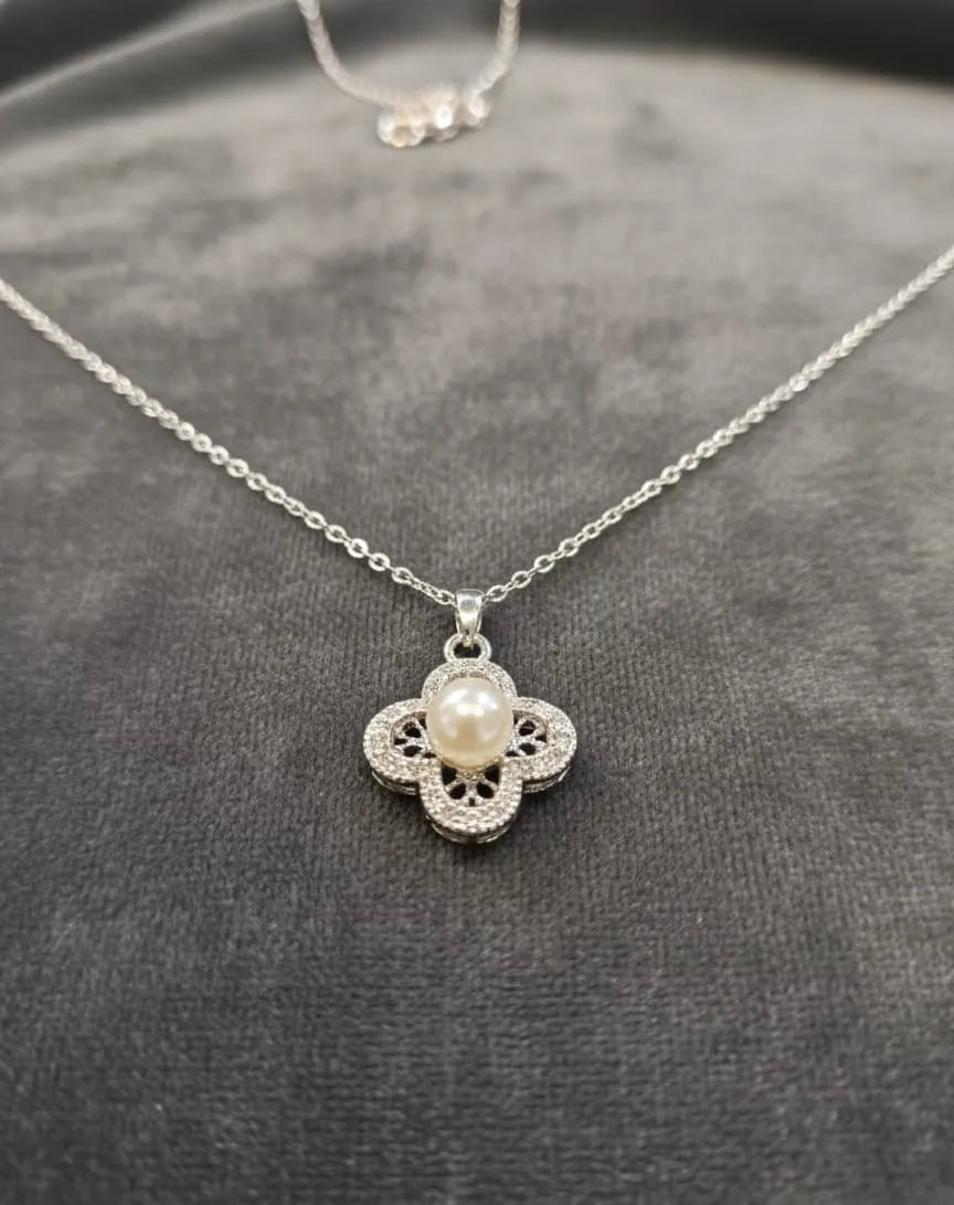 Silver necklace with a floral pendant featuring a pearl on a gray surface