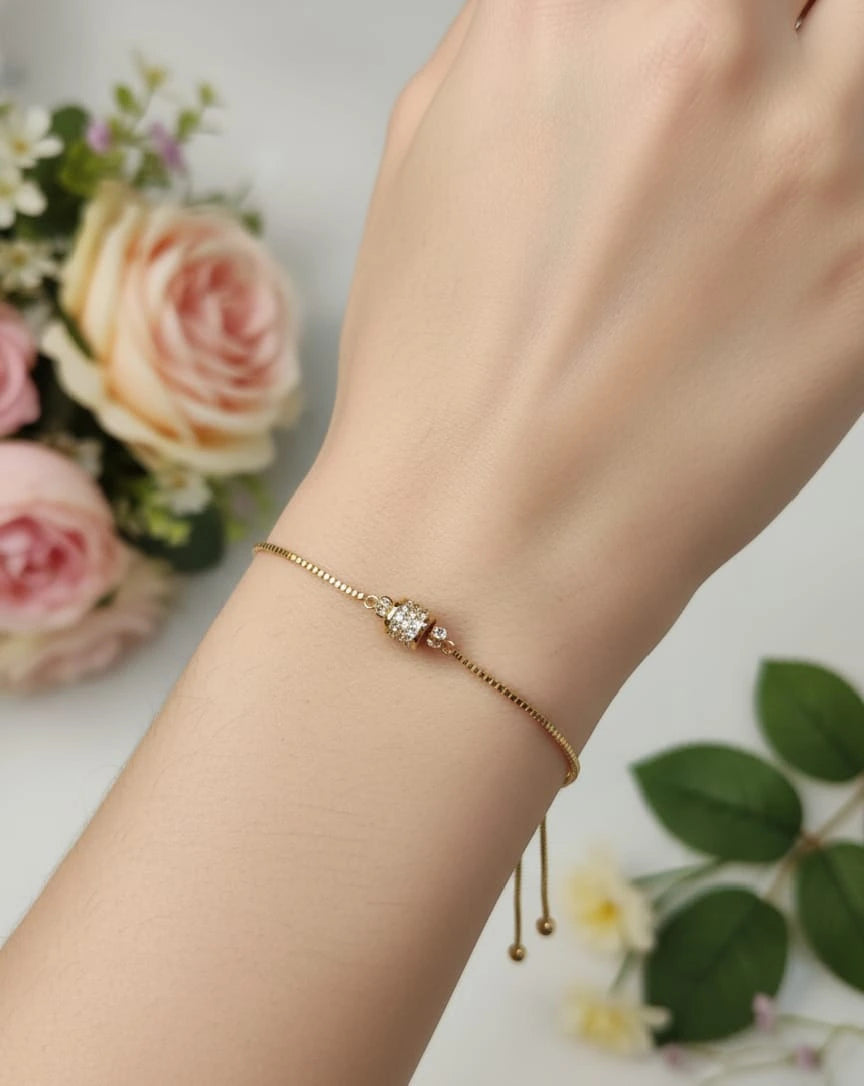 Gold bracelet on a wrist with flowers in the background