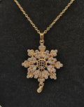 Gold snowflake pendant necklace on a black background