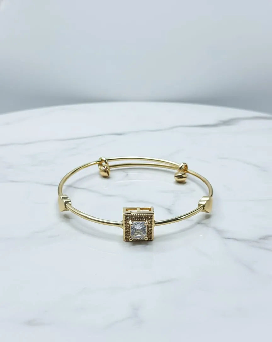 Gold bracelet with a diamond on a person's wrist, wearing a black outfit.