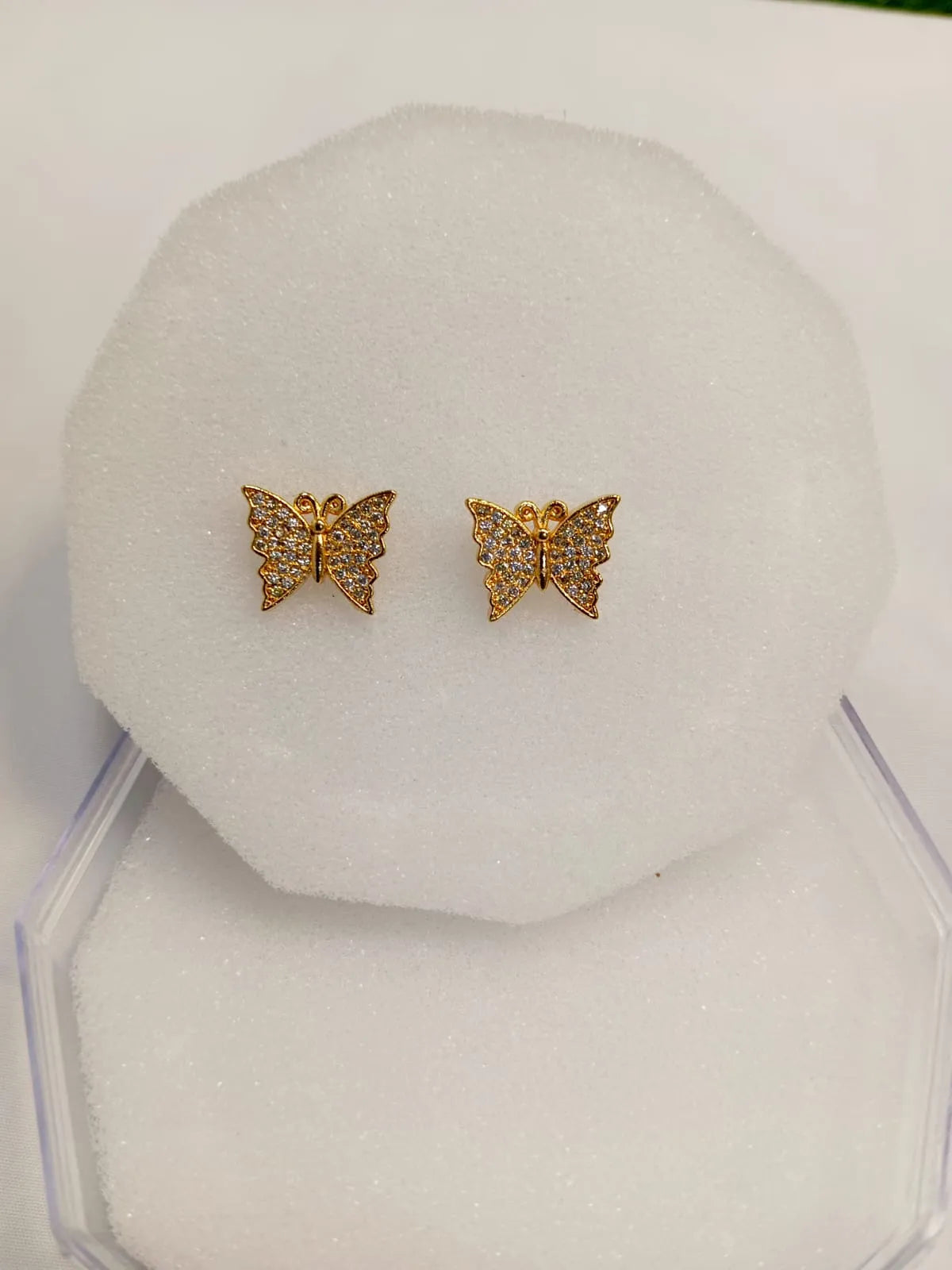 Gold butterfly earrings on a white jewelry display