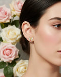 Close-up of a woman wearing earrings with flowers in the background