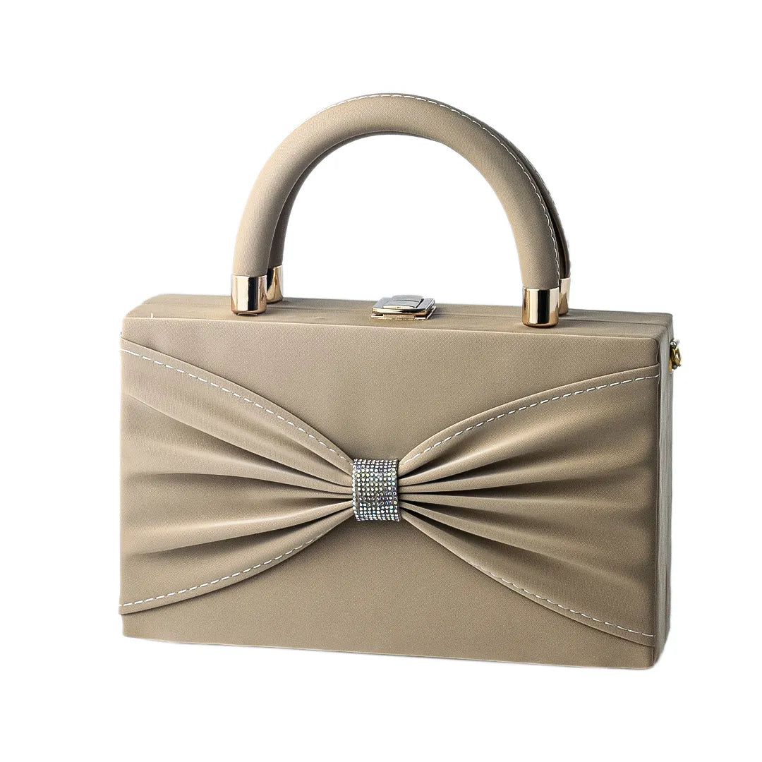 Beige handbag with a bow detail on a reflective water surface