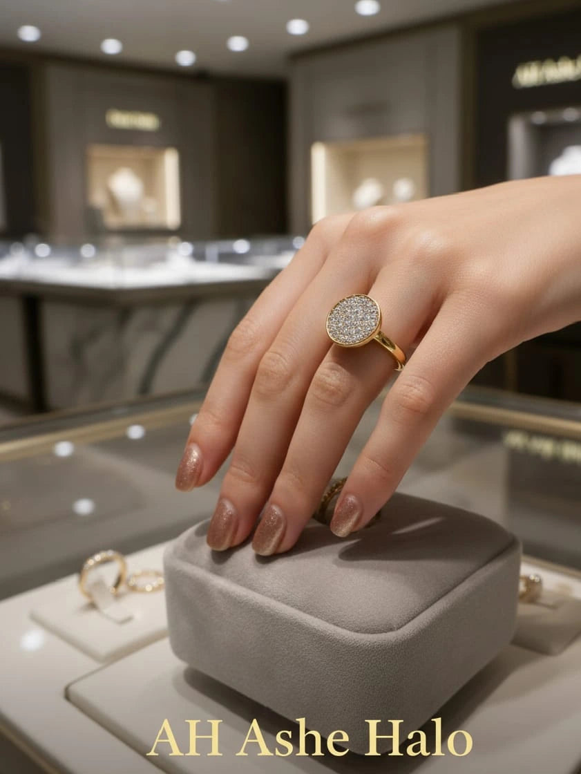 Gold ring with 'AH Ashe Halo' on a gray jewelry box in a store setting