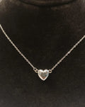 Silver heart-shaped pendant necklace on a black background
