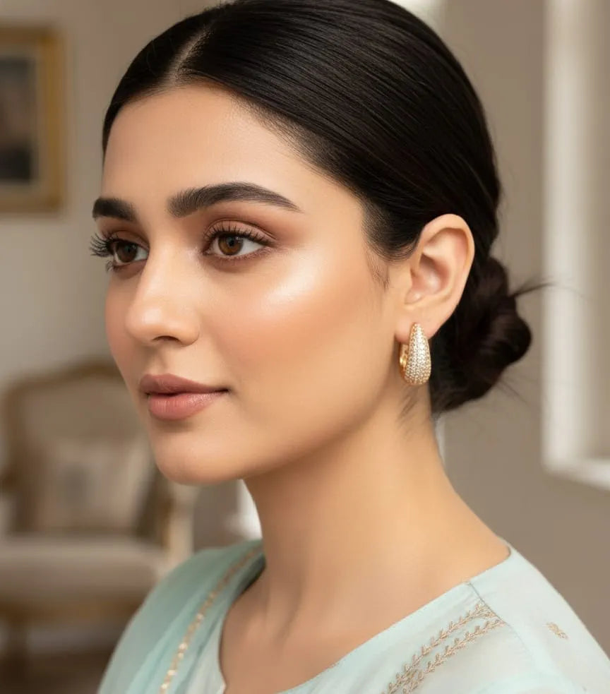 Woman wearing gold earrings in a blurred indoor setting