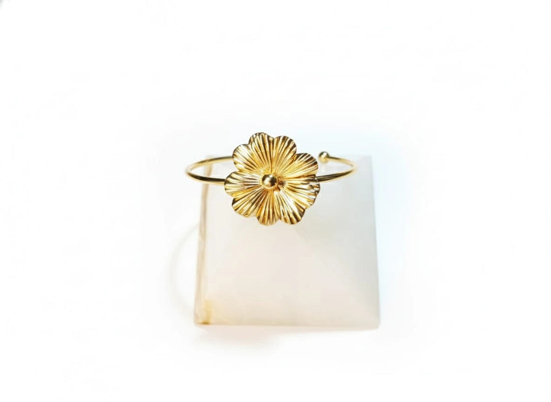 Gold bracelet with a floral design on a white background