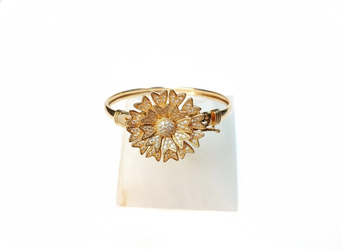 Gold bracelet with a sunflower design on a white background