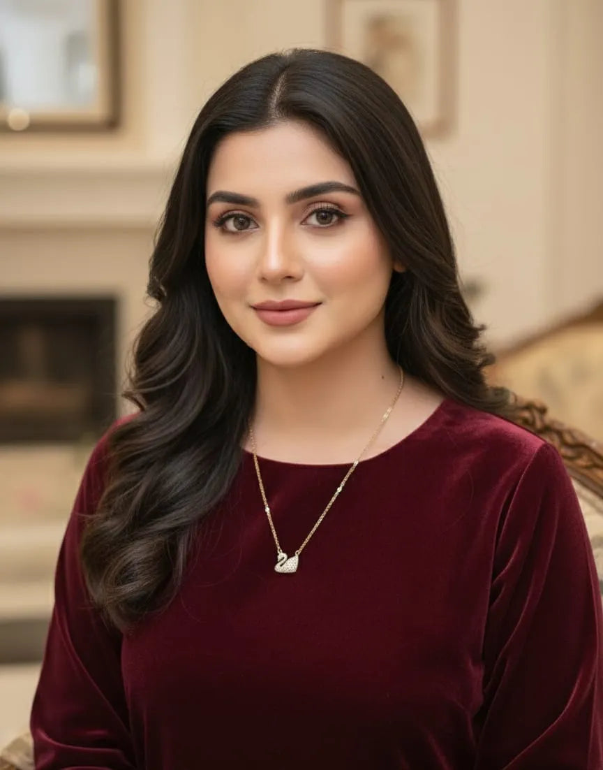 Woman wearing a burgundy top with a gold necklace in an indoor setting