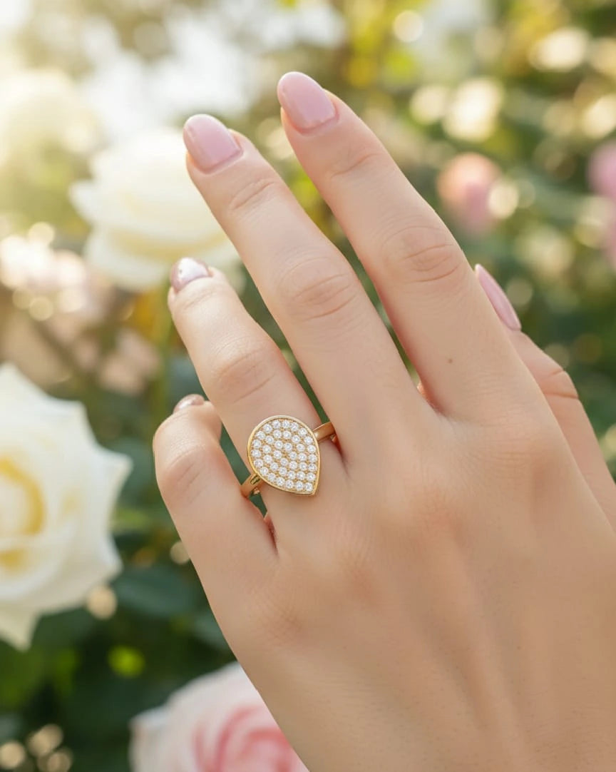 Hand wearing a gold ring with a diamond-like center, set against a blurred jewelry store background.