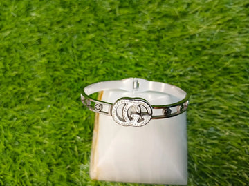 Silver ring with a prominent logo on a white stand against a grassy background