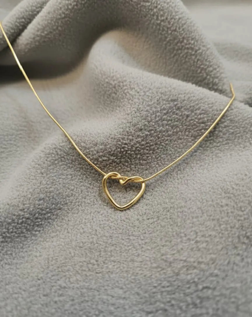 Gold heart-shaped necklace on a textured gray surface