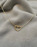 Gold heart-shaped necklace on a textured gray surface