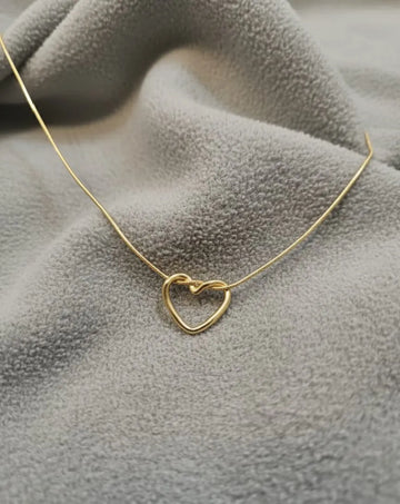Gold heart-shaped necklace on a textured gray surface