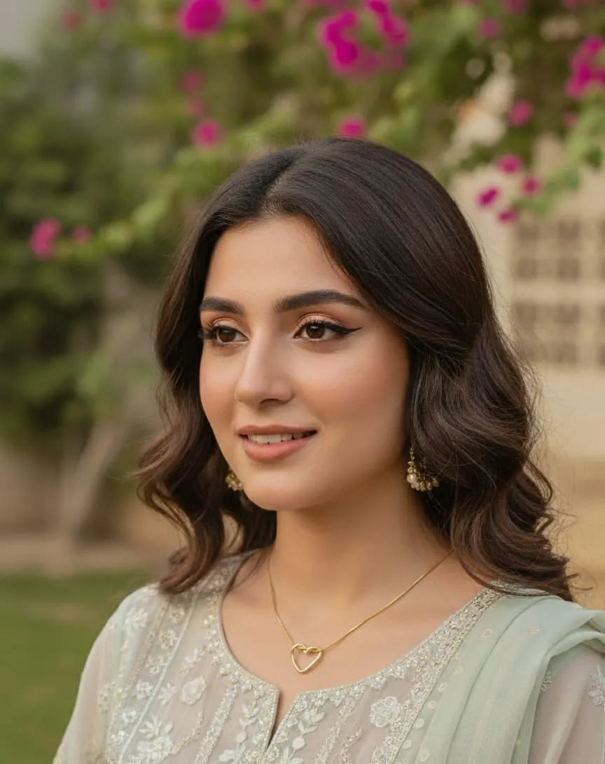 Gold heart-shaped necklace on a textured gray surface