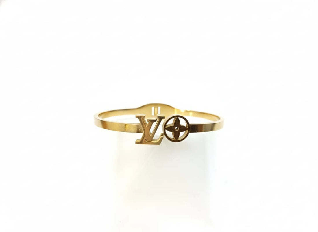 Gold bracelet with a brand logo on a white background