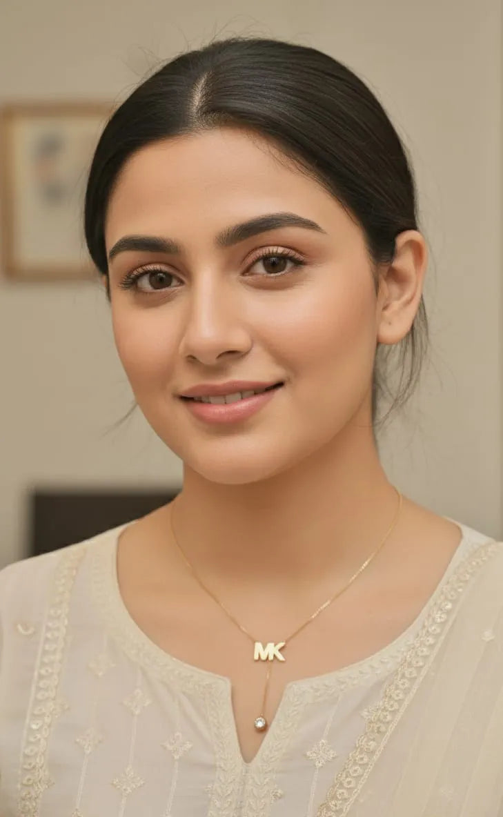 Woman wearing a necklace with a 'MK' pendant indoors