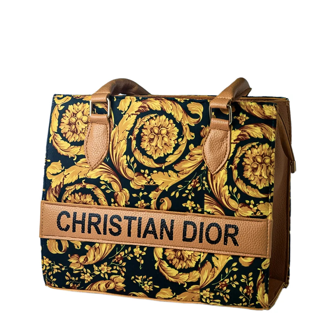 Christian Dior handbag with gold and black design on a marble table with green plants.