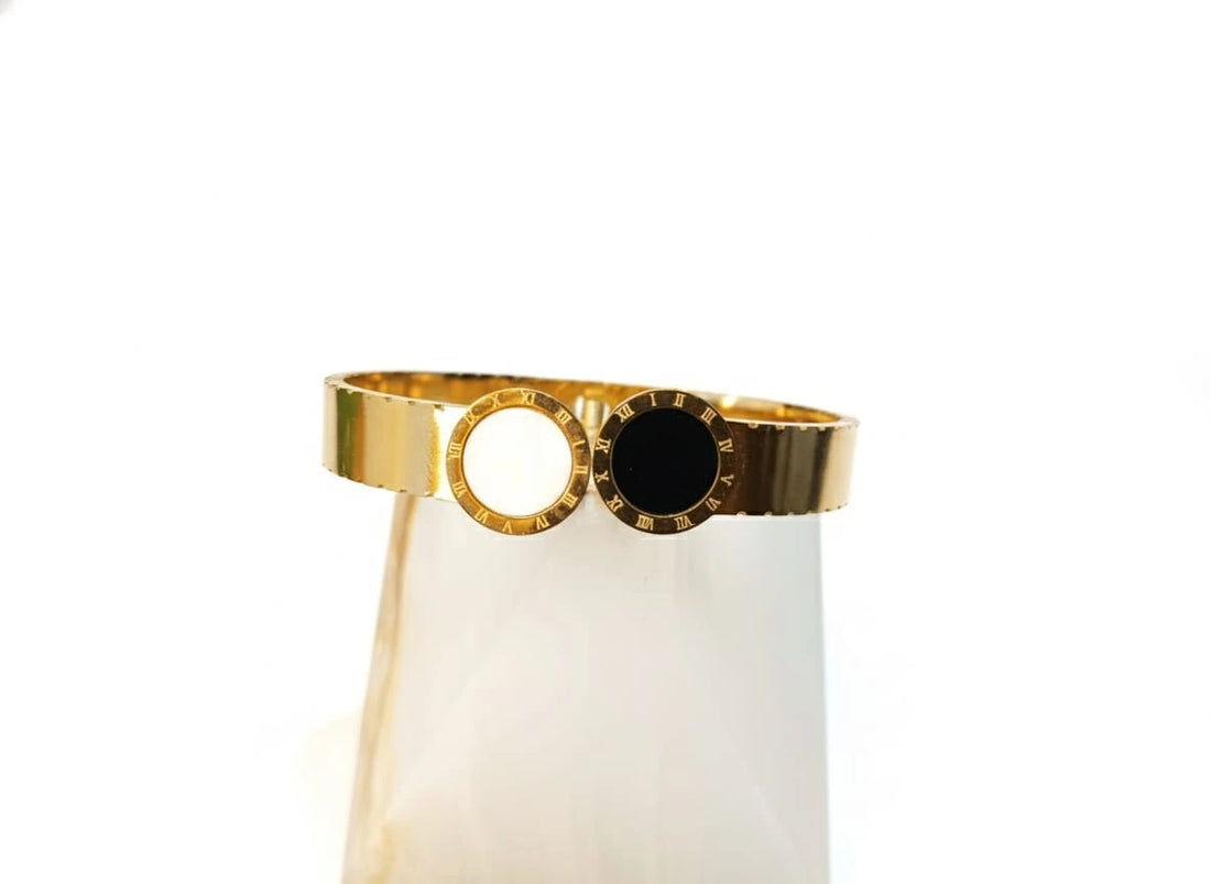 Gold bracelet with a black center on a white background