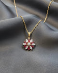 Gold necklace with a red and white gemstone pendant on a gray fabric background