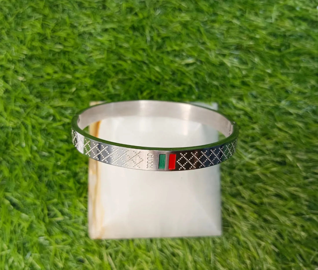 Silver bracelet with colorful band on a white box against a grass background