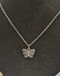 Silver butterfly necklace on a dark gray background