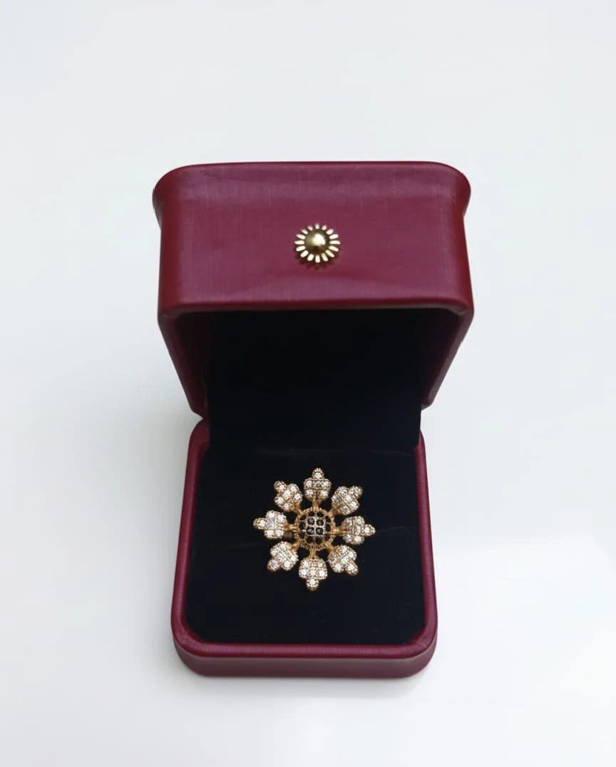 Gold brooch in a burgundy jewelry box on a white background