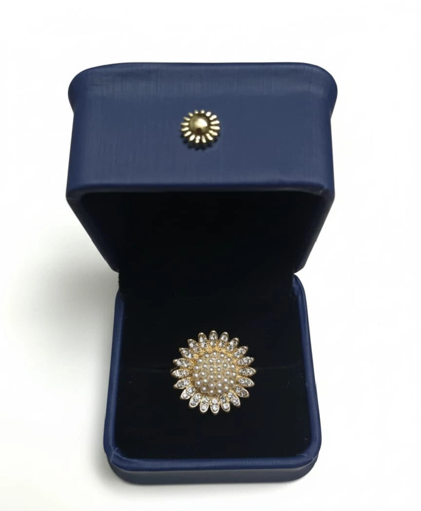 Gold brooch with pearl details in a blue jewelry box on a white background